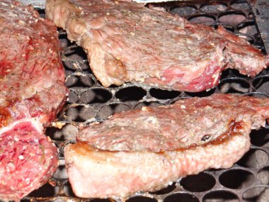 Çiğ bifteğin kalın kesimleri kızartılıyor, mermer ve dokusunu gösteriyor..