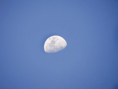 Kısmen aydınlanmış Ay 'ın detaylı bir görüntüsü engin, berrak, mavi gökyüzüne karşı durmaktadır..