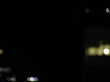 Odaklanamayan şehir ışıkları karanlık bir gece gökyüzüne karşı bir bokeh etkisi yaratır..