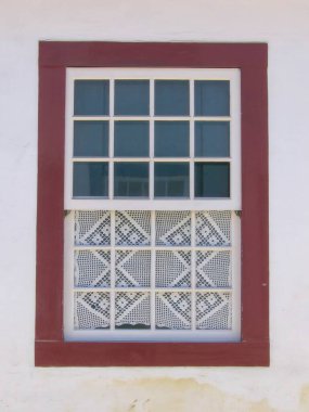 Kırmızı çerçeveli bir pencere dekoratif desenli camların üzerinde cam bir ızgara içerir..