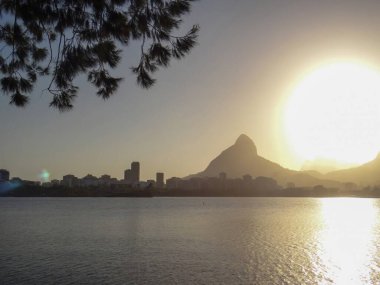 A picturesque sunset casts a warm glow over the Rio de Janeiro skyline and its iconic mountain peak.