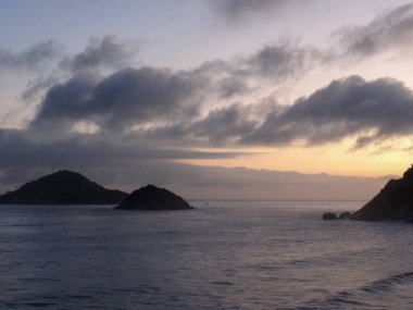 Alacakaranlık sırasında bulutlu bir gökyüzünün altındaki adaların manzarası huzurlu bir manzara yaratıyor.