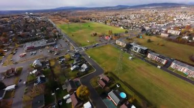 FPV insansız hava aracı sinemalı bulutlu gökyüzü altında banliyö sokaklarında ve tarlalarda süzülüyor