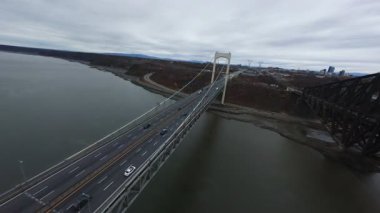 Bulutlu ışık altında geniş bir nehri geçen ikiz köprülerden oluşan hava manzarası. Modern mimarinin sinematik görüntüsü 4k.