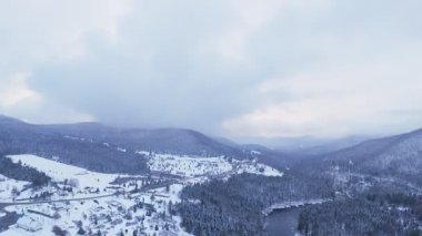 Buzlu bir nehir ve karlı dağ zeminiyle bir orman kanyonunun havadan görünüşü.