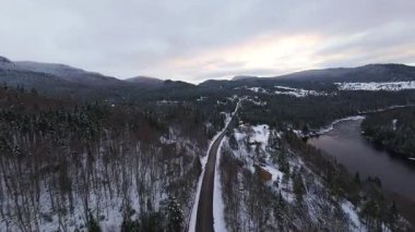 Yavaşça kıvrılan dağ nehri olan geniş karlı bir vadinin sinematik görüntüsü..