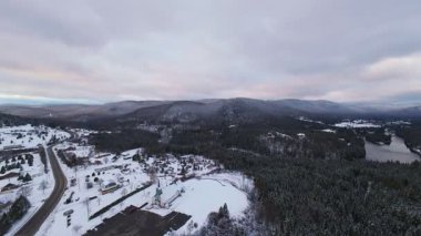 Parlak beyaz karlı araziyi kesen koyu buzlu bir nehrin sinematik yukarıdan görünüşü.
