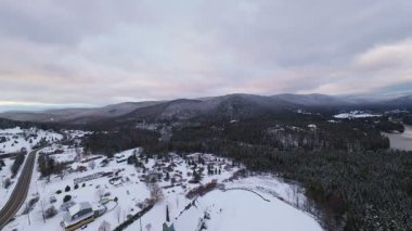 Karlı dağların sinematik kış manzarası ve yumuşak beyaz gökyüzünün altında dolambaçlı sakin bir nehir..