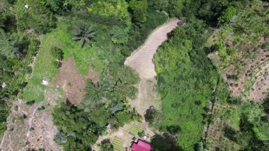 Sungai Penuh, Jambi, Endonezya 'daki tropikal ormanlarla çevrili yamaç manzarası. Highland bölgesinde teraslı arazi kullanımı, yeşil bitki örtüsü ve sürdürülebilir tarım gösteriliyor.