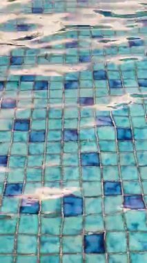 Yumuşak su hareketleri ve yumuşak yansımaları olan mavi yüzme havuzu fayanslarının rahatlatıcı soyut görüntüleri, refah, spa, yaz ve seyahat temaları için rahatlatıcı bir arka plan dokusu yaratır..