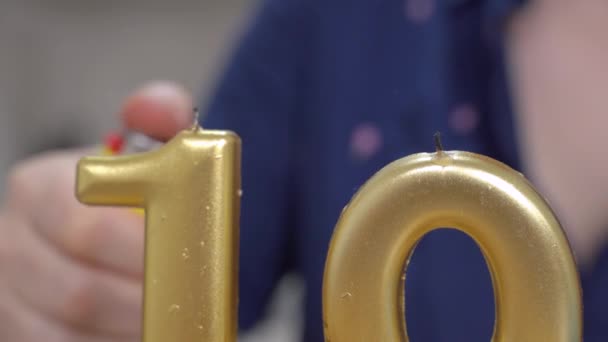 Κοντινό πλάνο ανθρώπινο χέρι ανάβει δύο εορταστικά χρυσά κεριά στο σχήμα του αριθμού δέκα. Έννοια επετείου ή πάρτι γενεθλίων — Αρχείο Βίντεο