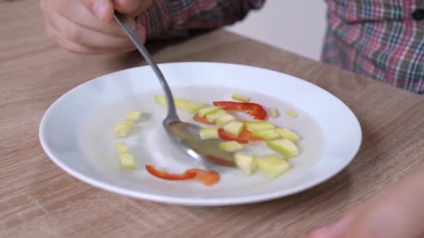 De persoon op dieet probeert gezond maar smakeloos vegetarisch voedsel te eten. Menselijk roert roestig groentesoep in kom met lepel, close-up. Vrijgezel maakte verschrikkelijk diner — Stockvideo