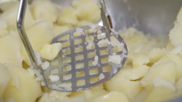 ステンレス製のジャガイモのマスターを使用してクリームやミルクでピューレを作るプロセスを閉じます。料理ブログのためのおいしい野菜やベジタリアン料理を準備するためのステップバイステップのレシピ. — ストック動画