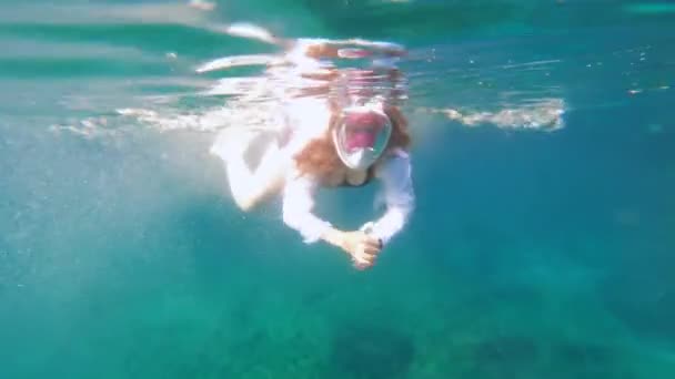 Giovane donna bionda in maschera da snorkeling e costume da bagno a due pezzi salta in mare e nuota sott'acqua, i suoi bellissimi capelli volano sciolti, vista frontale. Scatto subacqueo sulla action camera — Video Stock