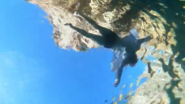 Girl swims and relaxes in sea during vacation, underwater shooting from below with action camera. Dead body of drowned woman floats on surface of water — 图库视频影像