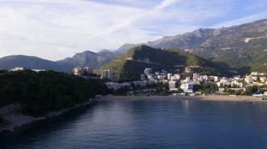 Deniz ya da okyanus kıyısında küçük bir kasabayla güzel bir dağ manzarası, yükseklerden uçan bir dron. Güneşli bir günde Bay ve City 'nin panoramik manzarası heyecan verici. Budva, Karadağ.