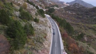 Araba dar bir yolda, uzaktan, dikiz aynasından İHA ile ateş ediyor. Hafta sonu gezisi. Sonbaharda seyrek orman ve kuru otlarla kaplı dağların güzel manzarası.