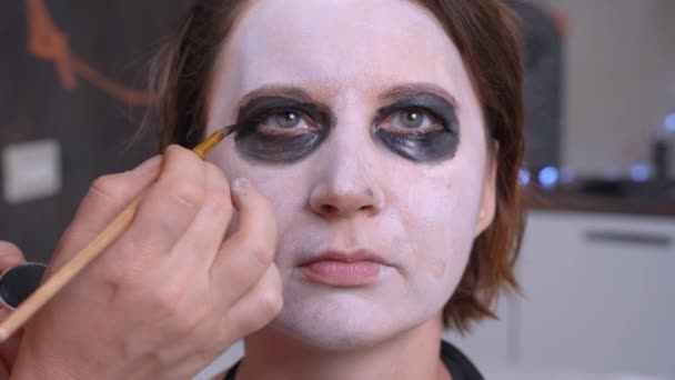 El maquillador profesional aplica el maquillaje insólito a los ojos de la actriz para rodar la escena de la película de terror o la producción teatral. Preparación para la fiesta de disfraces de Halloween — Vídeo de stock