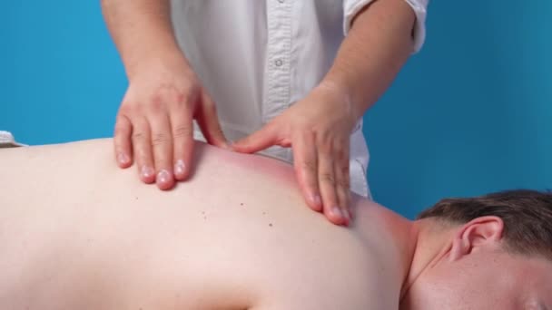 Patienten genomgår en hälsoförbättrande behandling med kiropraktor. Massör intensivt massage och knådar trött och värkande nack- och ryggmuskler, närbild. — Stockvideo
