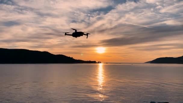 İnsansız hava aracı havada süzülüyor, sistem ve pervanelerin işleyişini kontrol ediyor ve şafak veya gün batımında güzel deniz manzaralarının fotoğraflarını çekmek için havalanıyor. — Stok video