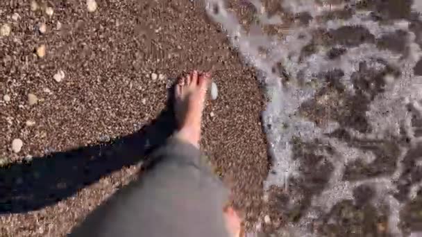 Persona con los pies desnudos caminando a lo largo de la playa bañada por olas de mar espumosas, vista superior. Fin de semana sin preocupaciones. Tiempo libre para reflexionar y meditar. Buena vida en la jubilación — Vídeo de stock