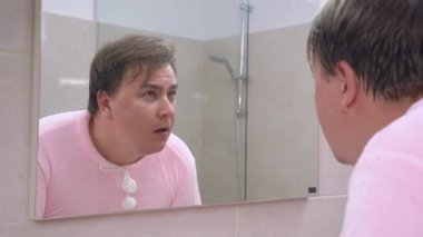 Pembe pijamalı genç adam sabah uyandıktan sonra ya da akşam yatmadan önce yüzünü banyoda yıkar. Garip bir ses adamın dikkatini çekti.