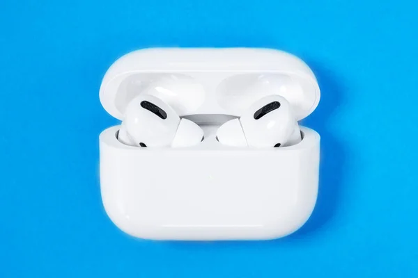 Rostov, Russia - July 06, 2020: Wireless headphones Apple AirPods Pro in opened charging case with active noise cancellation immersive sound, on blue background, copy space — Stock Photo, Image