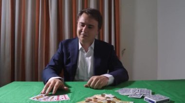 Resmi takım elbiseli genç işadamı poker oynuyor, yeşil baize 'li iskambil kağıtlarının kazanan kombinasyonunu yapıyor ve zaferi kutluyor. Kişinin psikolojik bağımlılığı ile ilgili sorunlar