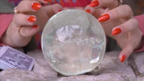 Hands of fortune teller with vulgar manicure on nails moving around magic glass ball. Oracle casts spell and conjures to predict future of client, close up — Stock Video