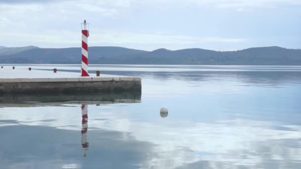 Deniz feneri denizde seyir yardımı olarak hizmet verecek, tehlikeli kıyı şeritlerini, tehlikeli sürüleri, resifleri, kayaları ve limanlara güvenli girişleri işaretleyecek. Suyun sakin ayna yüzeyi. — Stok video