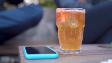 İş adamı kafedeki masadan limonatayı alır ve yerine koyar.