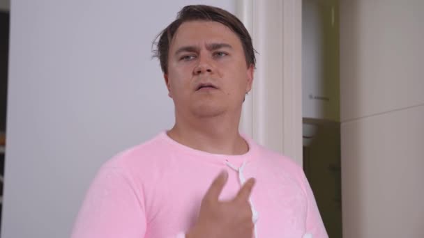 Young man in warm pink pajamas speaks sign language of deaf and dumb, shows someone love with gestures and that he will always be in his heart — Αρχείο Βίντεο