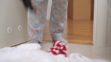 Pijamalı biri yere dachshund köpeğini koyar, onu uzaklaştırmak için tokat atar ve böylece evi temizlemeye engel olmaz, kapat.