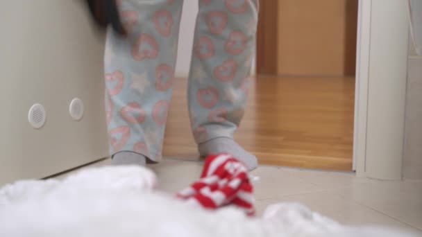 Pessoa em pijama coloca cachorro dachshund no chão, tapas para afastá-lo e para que ele não interfira com a limpeza em torno da casa, close-up — Vídeo de Stock