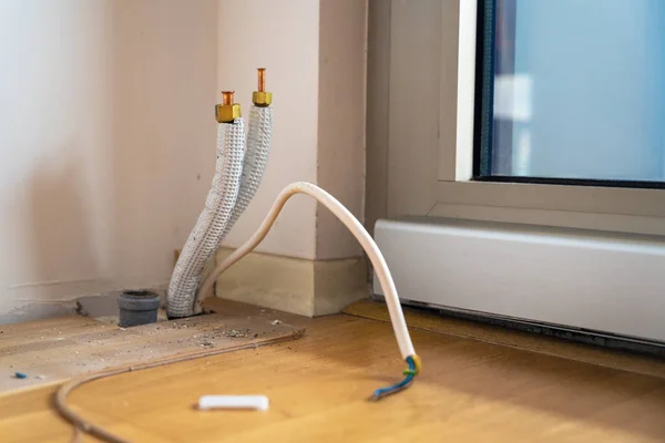 在新公寓的维修过程中，杂工制造电线、水管或安装空调。从地板上伸出来的电线和建筑碎片四处散落，密闭着 — 图库照片