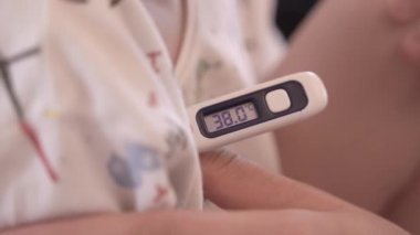 Dijital termometreyle hasta çocuğun ateşini ölçüyorum.