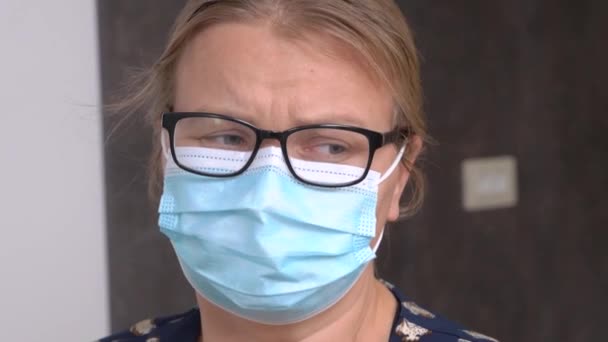 Ung blond kvinna i skyddande medicinsk mask gråter och skakar på huvudet tragiskt på grund av olycka. Hon sörjer den älskades sjukdom eller död. — Stockvideo