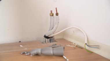 İşçi adam sünger kauçuk yalıtım kolunu tüpe koymaya çalışıyor ve kırık klimanın elektrik kablolarını kontrol ediyor..