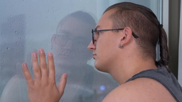 Aggressiver Mann blickt aus Fenster mit Wassertropfen übersät — Stockvideo