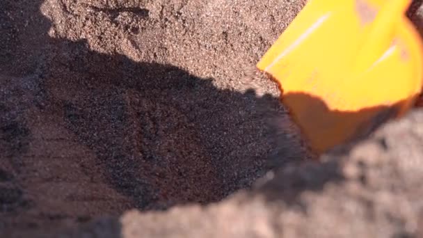 Kopanie wykopu w mokrym piasku z żółtą łopatą zabawki na plaży — Wideo stockowe