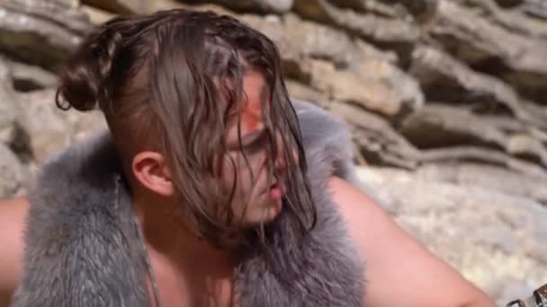 Caveman with long dirty hair smells ground holding spear — Stock Video