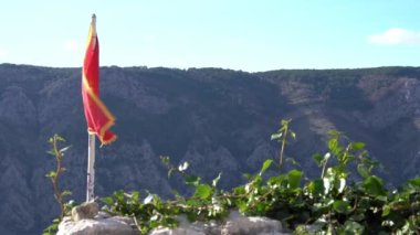 Karadağ 'ın kırmızı bayrağı, altın çift başlı kartal rüzgarda dalgalanan dağların tepesine dikilmiş, güneşli bir gün. Eski bir zafer geleneği.