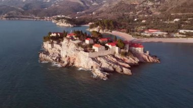 Sveti Stefan adasının hava gün batımı görüntüsü. Karadağ Sveti Stefan adası insansız hava aracı manzaralı. Meşhur seyahat yeri