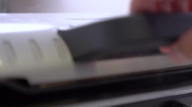 Adam ızgaranın kapağını hafif mutfakta köfte kızartarak açıyor.