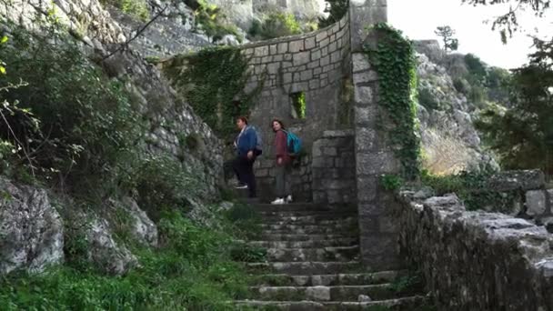 Turisté s batohy vylézt staré kamenné schody ve středověku zničený hrad prozkoumat krásné architektonické památky. Cestování do historických míst — Stock video