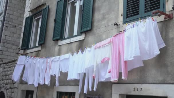 Ren tvätt hänger på tygrep vid gamla byggnadsfönster — Stockvideo