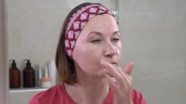 Ώριμη γυναίκα εφαρμόζει φυσικό τρίψιμο στο πρόσωπο στο μπάνιο — Αρχείο Βίντεο