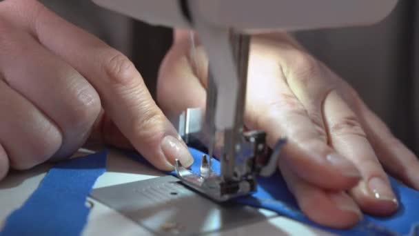 Tailor repairs or makes new clothes using professional sewing machine, close up, top view. Person stitches border seam on the edge of fabric and checks it — Stock Video