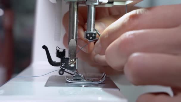 Persona está tratando de insertar la aguja en una barra de la máquina de coser en preparación para el trabajo, de cerca, vista lateral. Atelier para la fabricación y reparación de ropa — Vídeos de Stock