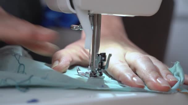 Skräddarsydda reparationer eller gör nya kläder med hjälp av professionell symaskin, närbild, ovanifrån. Personsömmar kantsömmen på tygkanten och kontrollerar den — Stockvideo